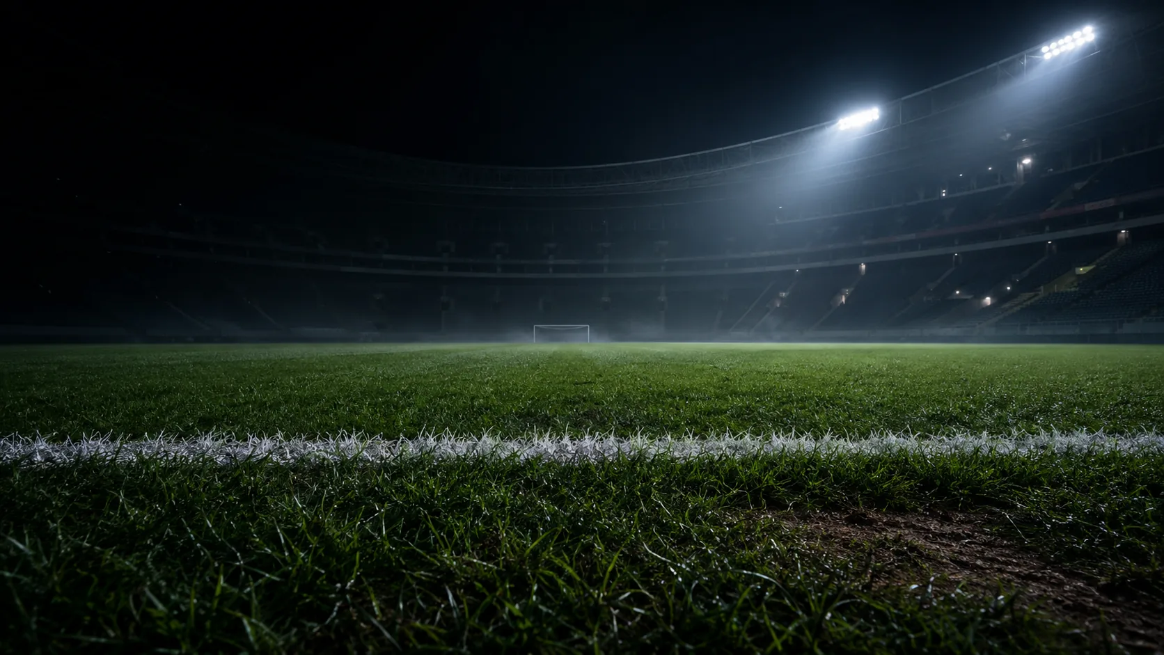 An empty football pitch in late golden-hour light, photographed from behind one goal.